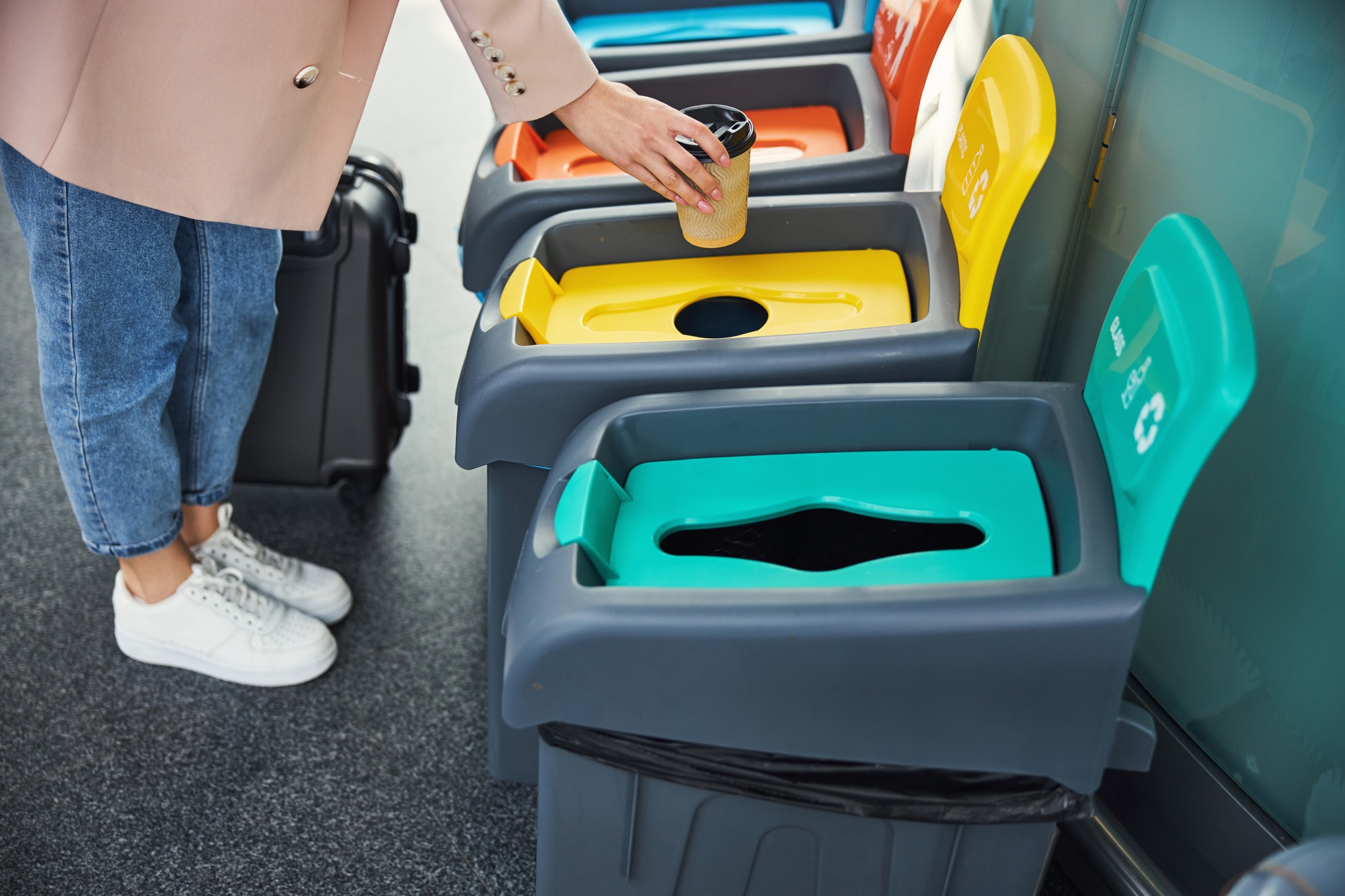 Female passenger throwing coffee cup in trash can at airport