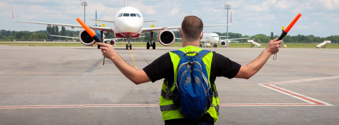 Aviation marshaller meets airplane at the airport. Airport worker. Modern airport. Aviation business