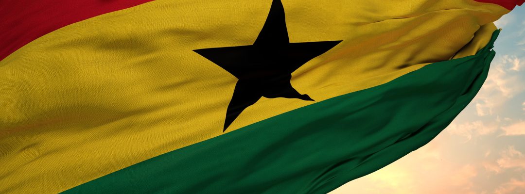 Closeup view of the waving flag of the Ghana on a background of sunset